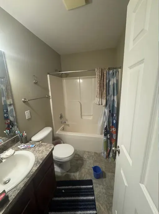 ACG bathroom before renovation: tub with shower curtain and dated vanity
