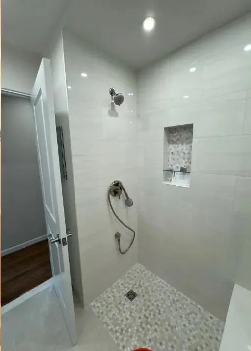 ACG bathroom after renovation: walk-in tile shower with niche and pebble floor