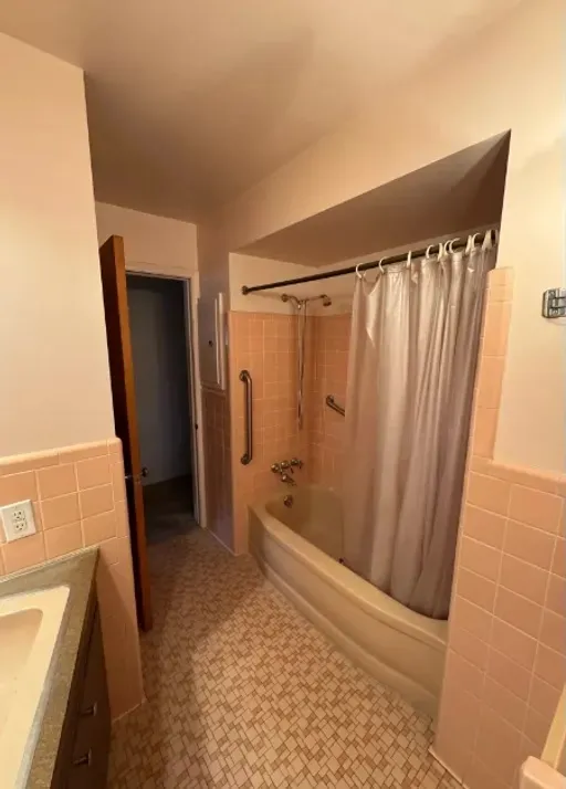 ACG bathroom before renovation: peach tile and tub with shower curtain