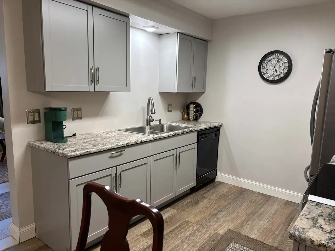 Renovated condo kitchenette with gray cabinetry and stone counters